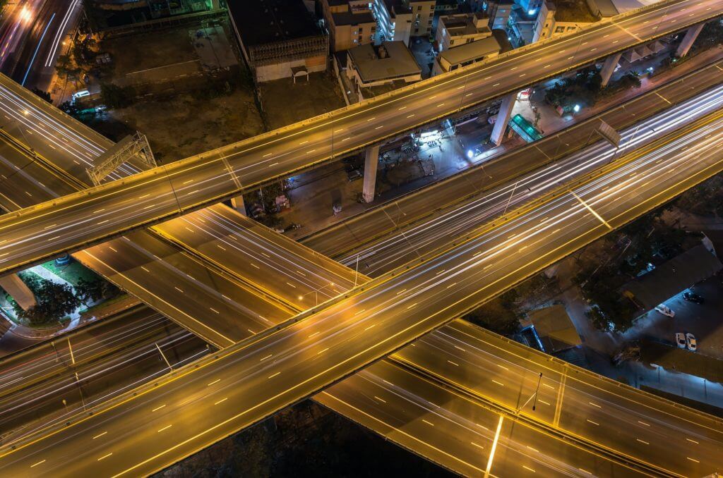 Top view of massive expressway at night with light of cars, transportation industrial concept